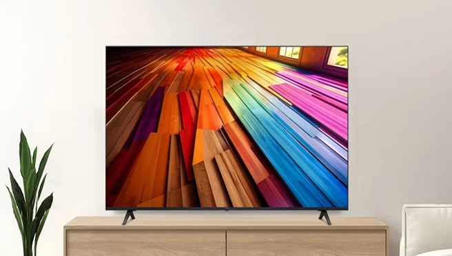 A large TV displaying colorful, abstract wooden plank art, resting on a wooden media console in a bright living room.