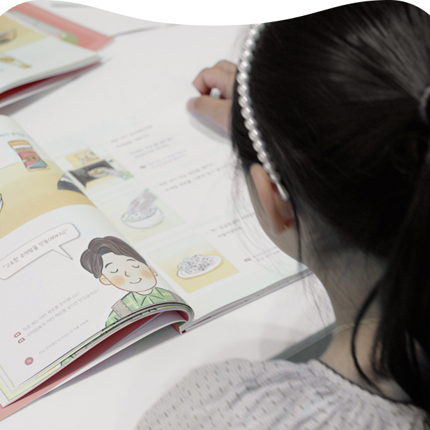 A learner reading the LG School easy-read book, filled with illustrations and speech bubbles, to learn how to use home appliances
