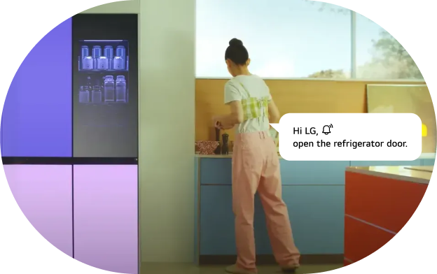 An image of the LG refrigerator AI voice command feature. A woman works in the kitchen with an LG refrigerator featuring a black upper section and purple lower section visible, along with a voice command speech bubble. Command: 'Hi LG! Open the refrigerator door.'