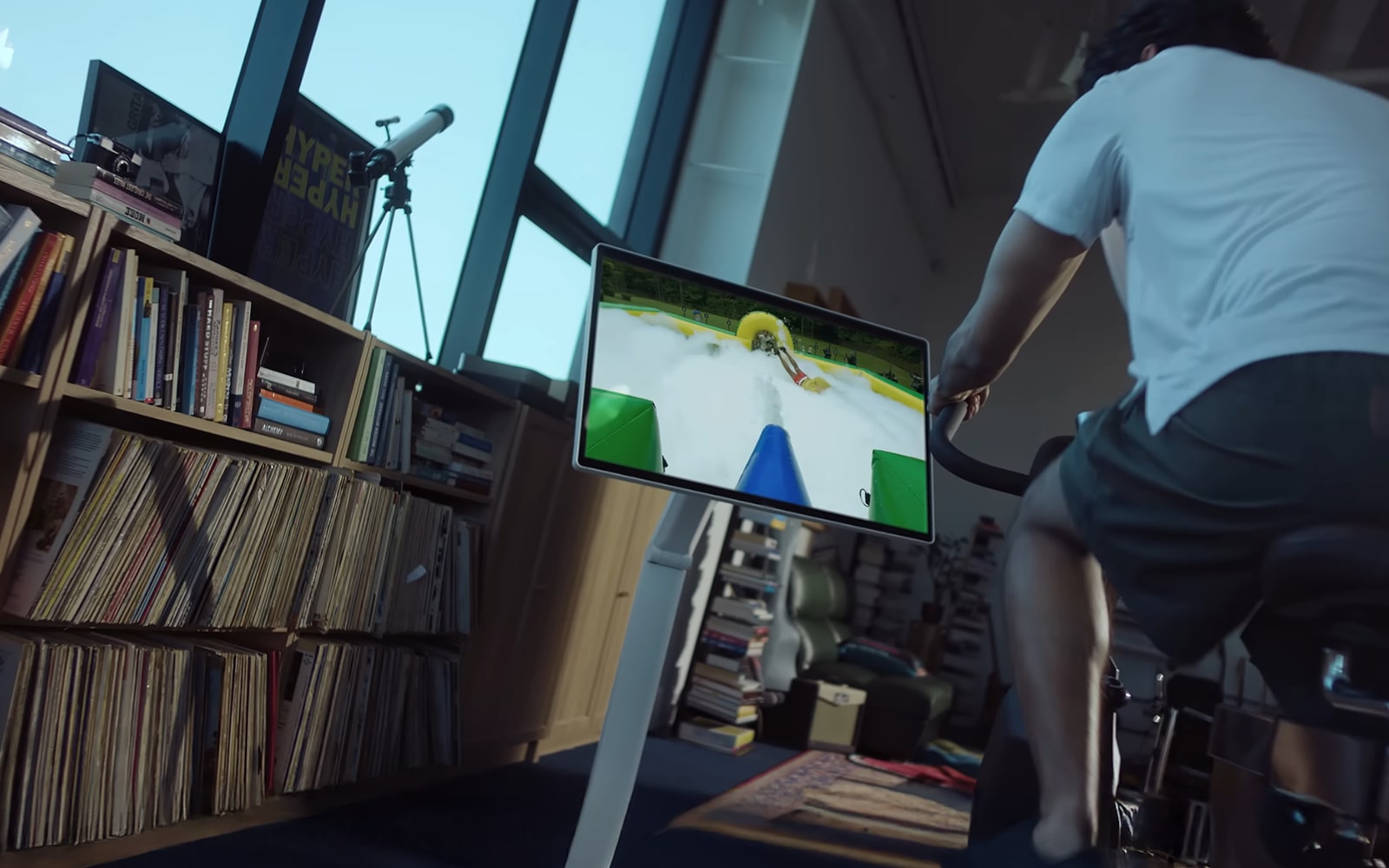 A man rides a stationary bike while looking at an LG 360 monitor.