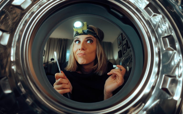 A woman trying to fix a washing machine