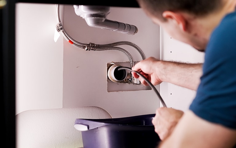 A man inspecting an LG washing machine drain.