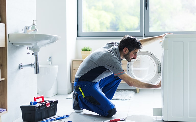 A man trying to fix a washing machine