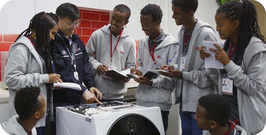 Young people are surrounding LG employees and listening to an explanation about washing machines.