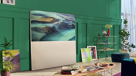 EASEL in Full View Mode leaning against a green living room wall and surrounded by art. There’s a scene of sand dunes on-screen.