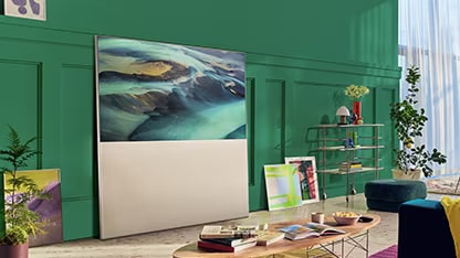 EASEL in Full View Mode leaning against a green living room wall and surrounded by art. There’s a scene of sand dunes on-screen.