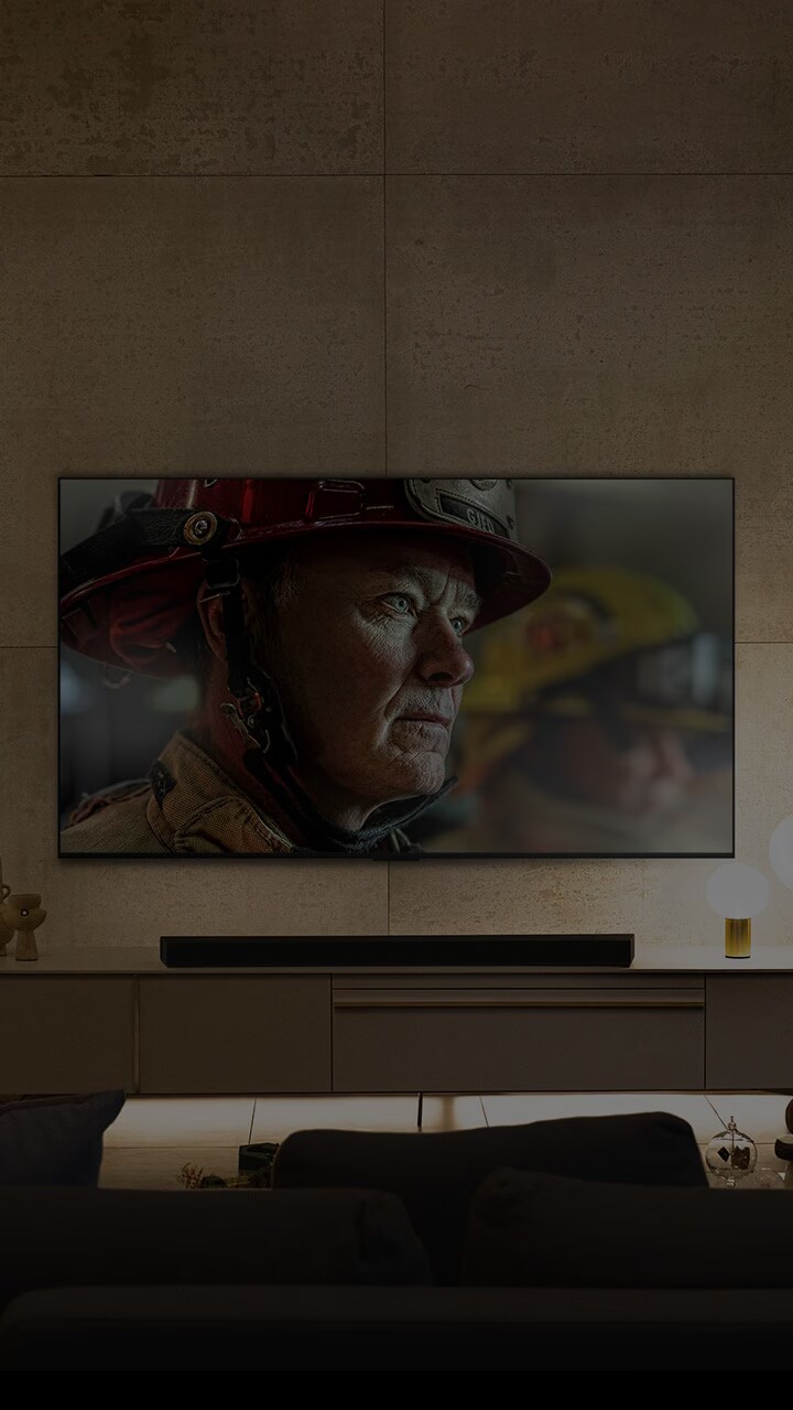 A wall-mounted LG OLED TV is in a white and bright room with natural decorations. As the screen moves, the scene changes from day to night. with Dolby Vision IQ logo