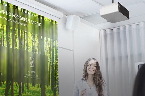 A tanár egy osztályban van és az LG probeam eszköz képernyőjét nézi