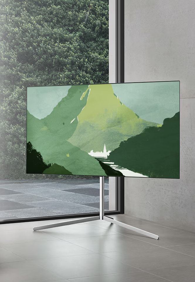 LG OLED televízió egy modern, szürke helyiségben egy medencére néző ablak előtt. LG OLED egy természetes nappaliban, ahol szabadon láthatók a téglák, a fa részletei és a növények.