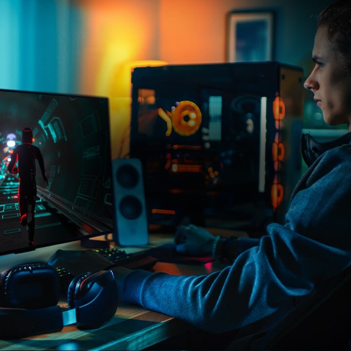 A person plays a sci-fi game at his personal desk on a small LG OLED television