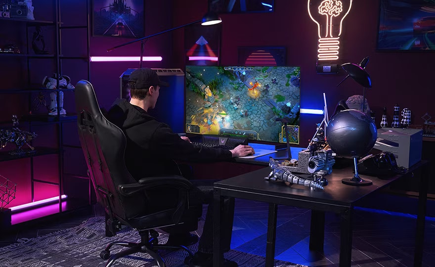 A man plays a game on the smallest LG OLED television while sitting at a desk