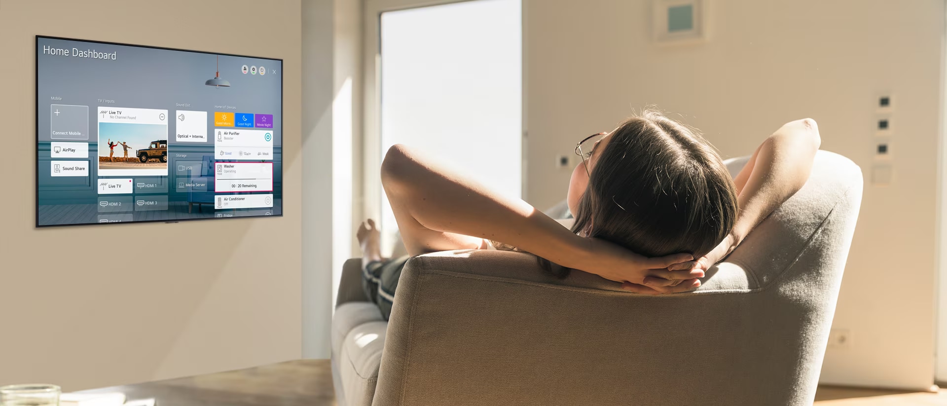 Mujer recostada en un sofá diciéndole a la TV que baje la temperatura con el Panel de inicio en la pantalla de la TV