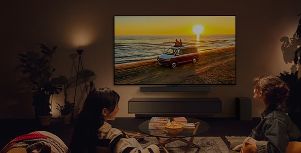 Mysigt rum med LG TV på väggen och två personer som sitter i soffan