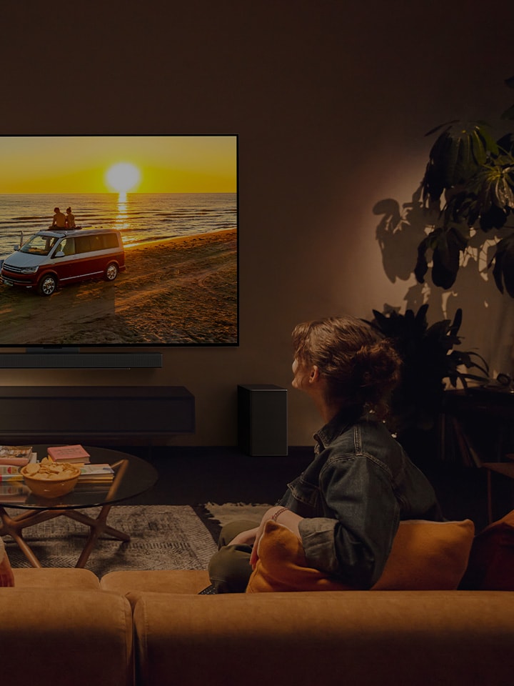 Två personer i ett stämningsfullt vardagsrum med en LG-TV på väggen. 