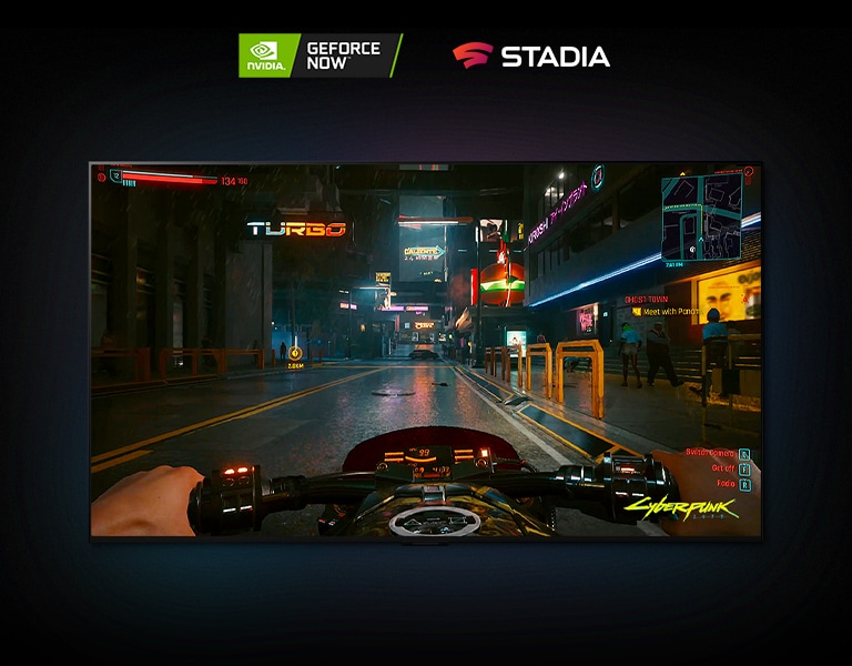 Ve scéně ze hry Cyberpunk 2077 zobrazené na displeji LG OLED projíždí hráč na motorce ulicí osvětlenou neony.