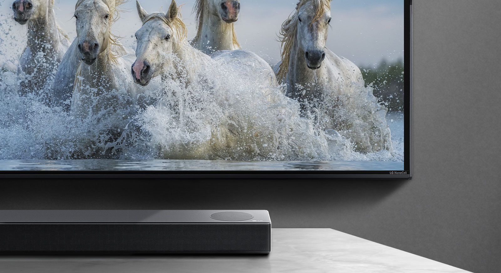 Polovina spodní obrazovky a polovina soundbaru. Na displeji televizoru běží bílé koně po vodě. 