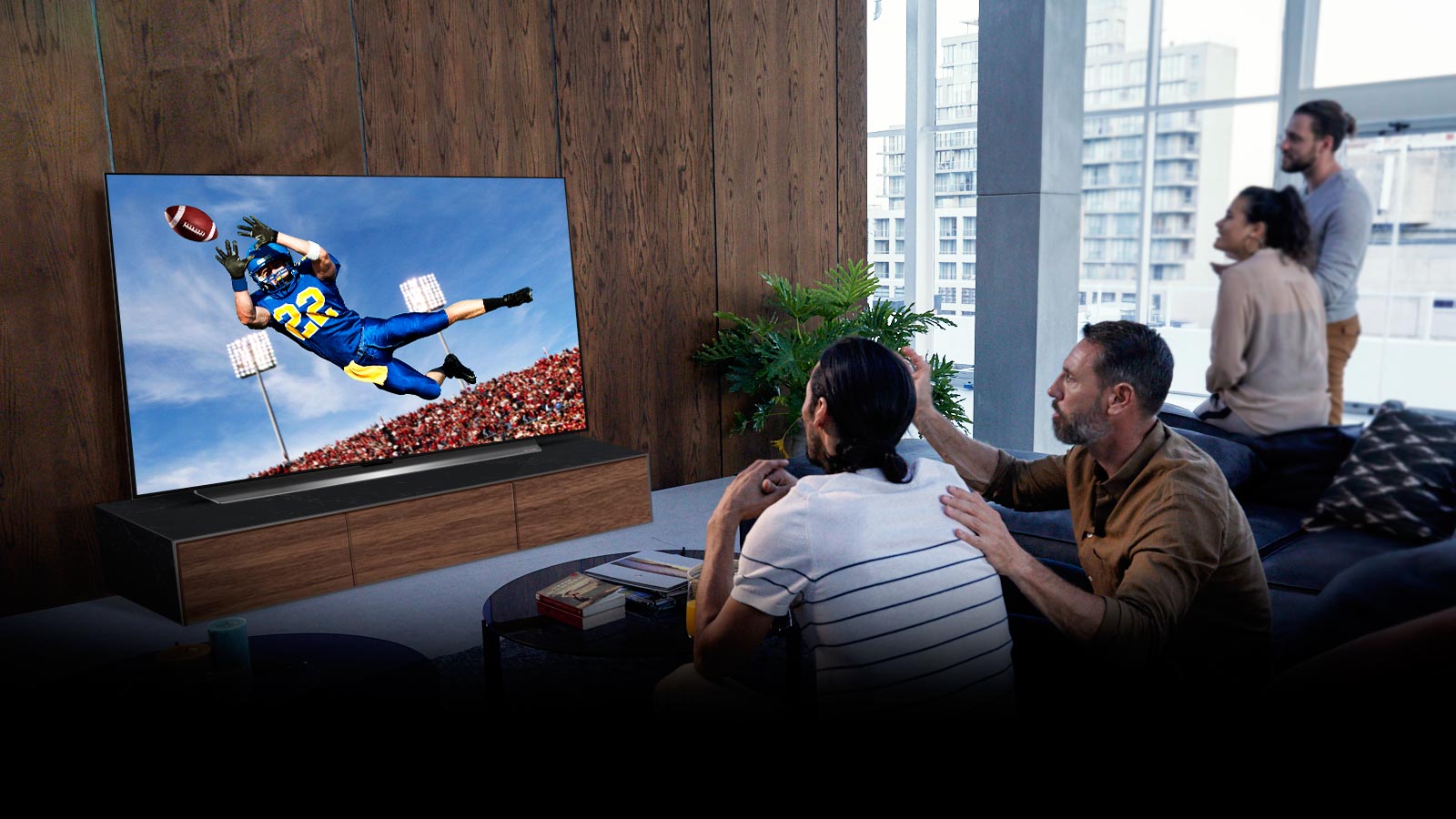 Lidé sledují americký fotbal v televizi v obývacím pokoji