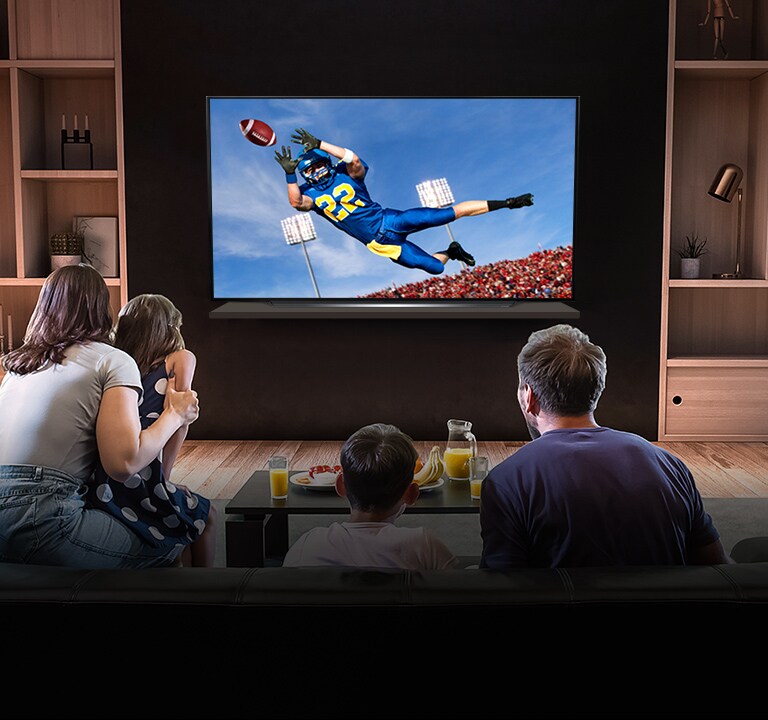 Lidé sledují americký fotbal v televizi v obývacím pokoji