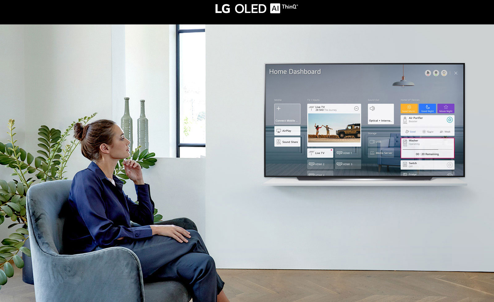 Žena sedící na křesle v obývacím pokoji a televizní obrazovka s funkcí Home Dashboard