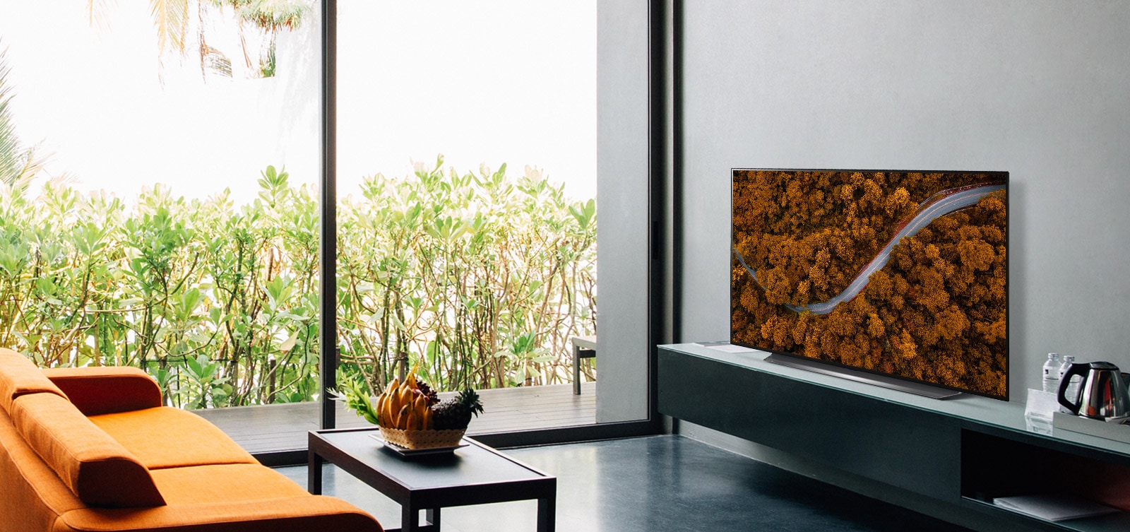 Luxusní obývací pokoj se sedačkou a televizorem, který zobrazuje letecký pohled na přírodu
