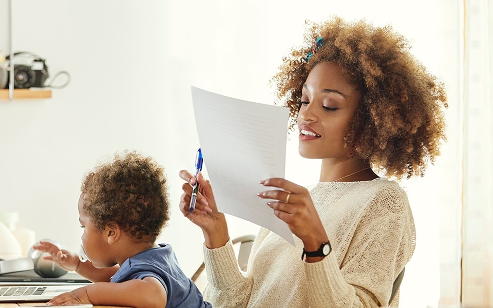 A mother trying to work from home and be productive whilst her baby sits on her lap