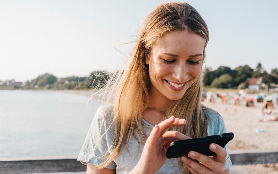 A woman checks the LG ThinQ app on her smartphone.