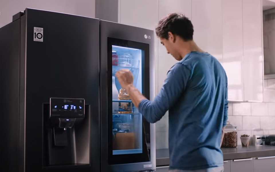 A man utilising the two-knock system on the mirrored glass panel revealing the content of the LG Instaview Door-In-Door Refrigerator.