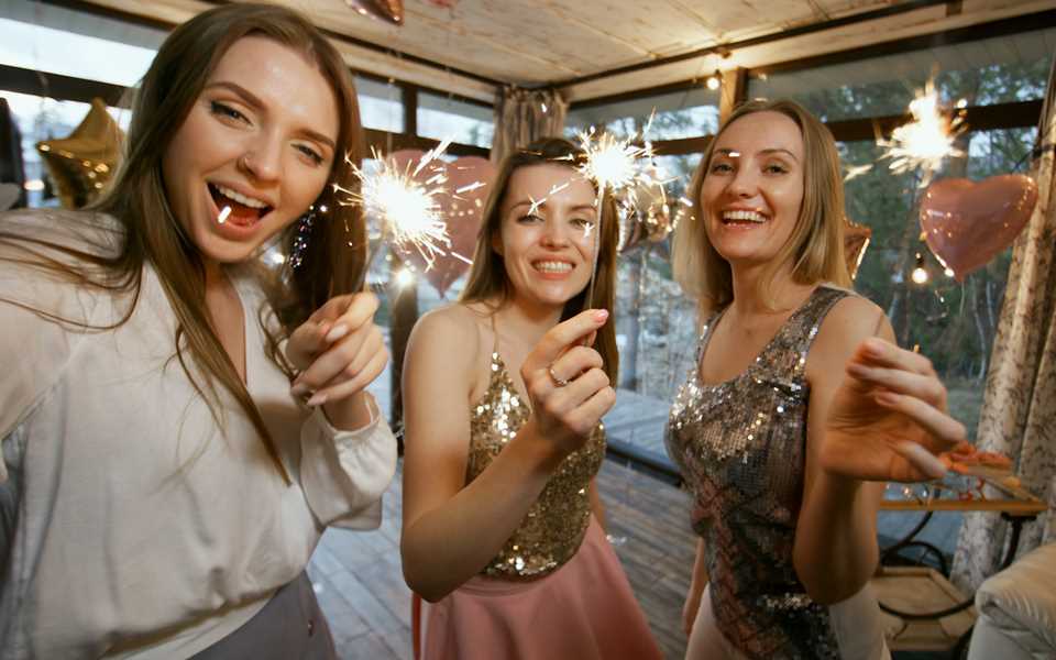 Three female friends taking a photo with the LG Velvet whilst holding sparklers 