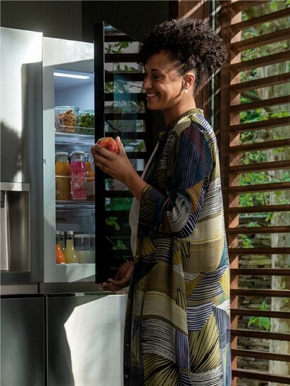Ein Bild einer Frau, die einen Apfel vor dem LG instaView Door-in-Door Kühlschrank hält.