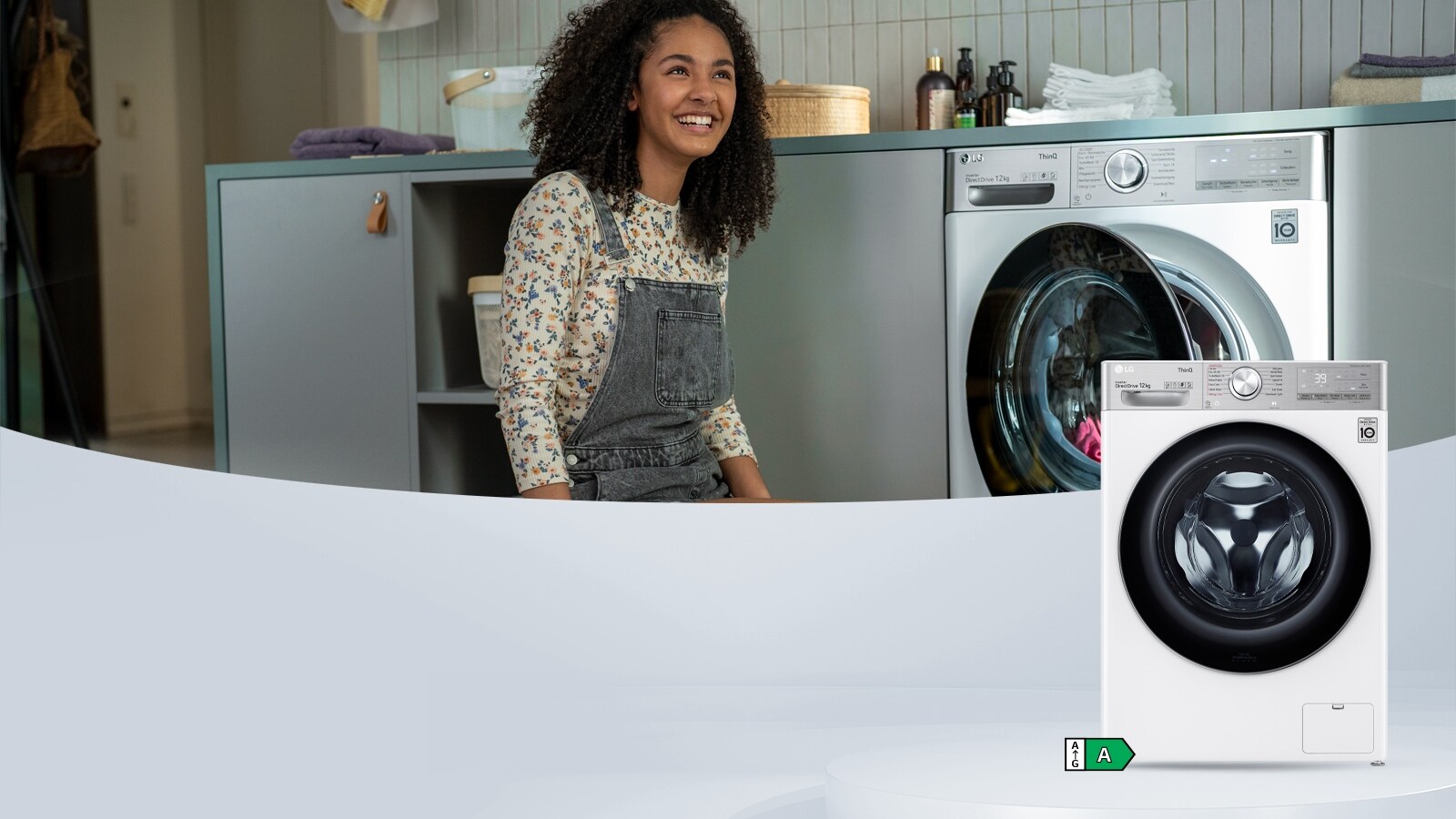 Ein Bild eines jungen Mädchens, das in einer Waschküche mit der neuen intelligenten LG Waschmaschine in Weiß und Splitteroberteil sitzt.