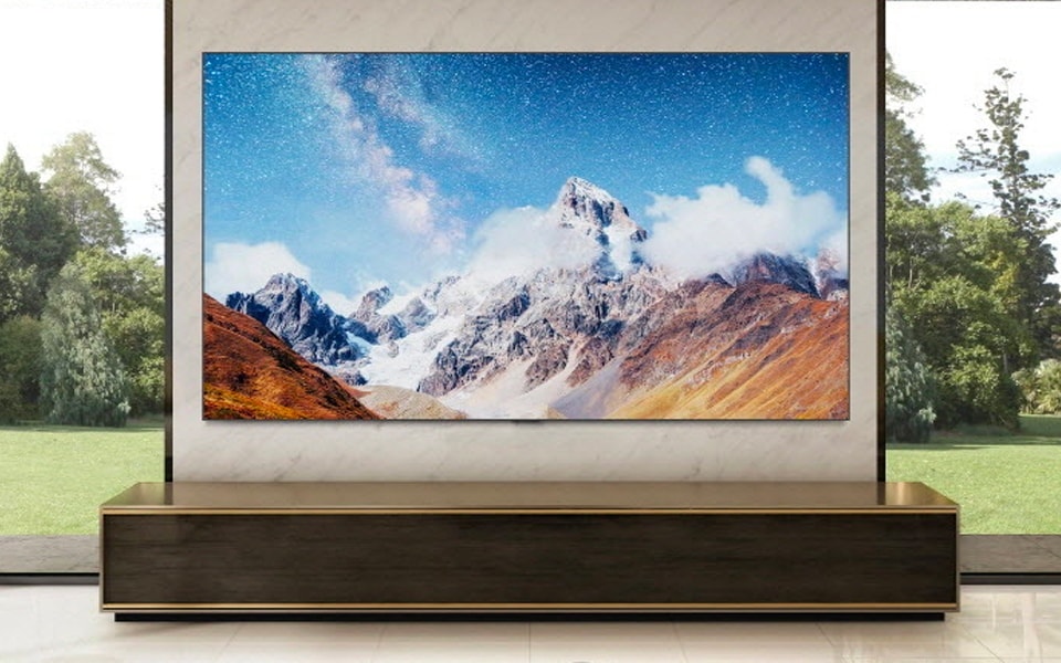 The LG OLED evo Gallery Edition is mounted on a wall between two windows