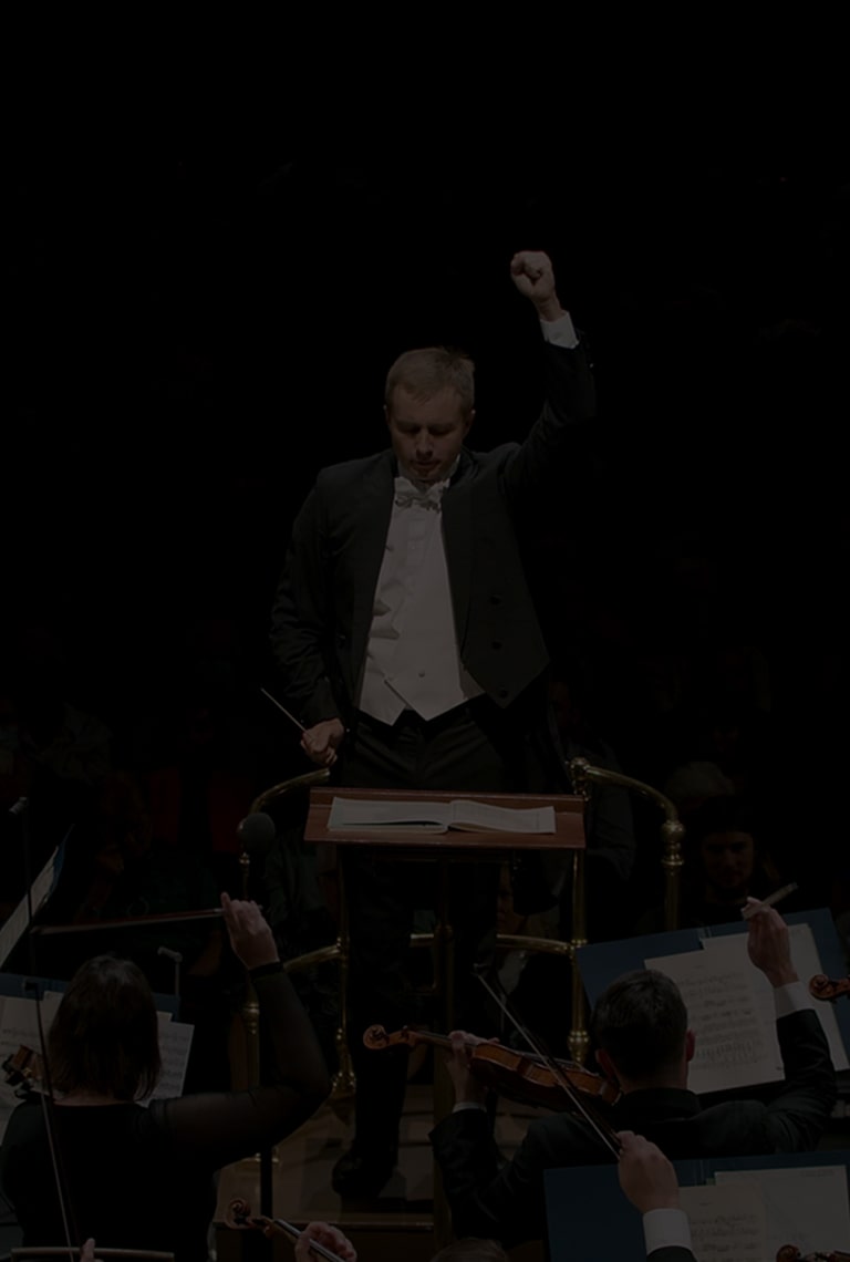 Ein Dirigent dirigiert ein Orchester. Darübergelegter Text: „Das musikalische Geschenk an die ganze Welt. #Musik #Partnerschaft”