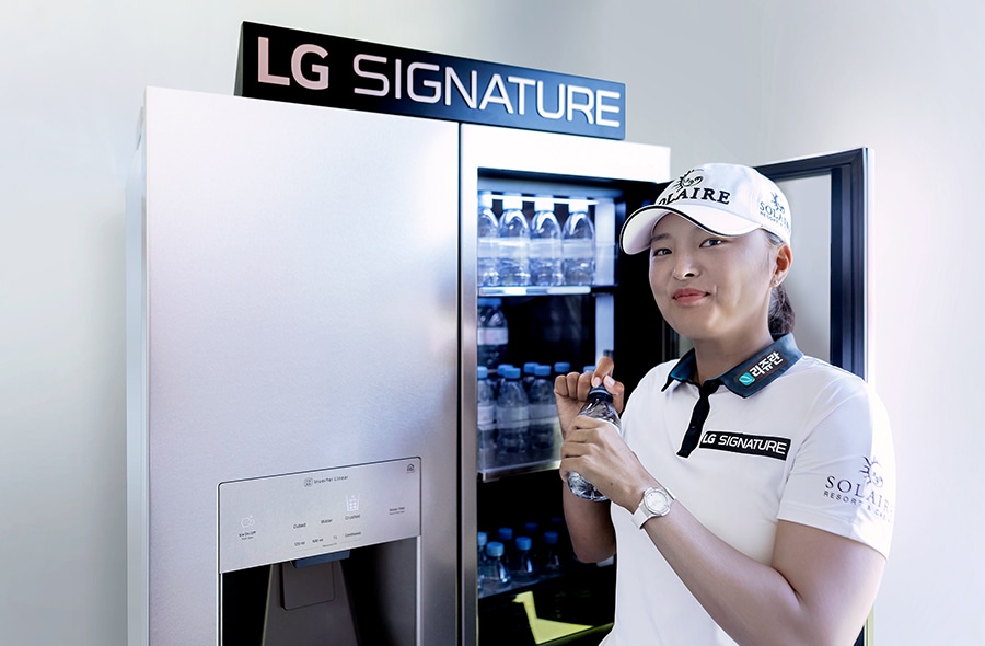 Jin Young Ko hält eine Flasche Wasser neben einem LG SIGNATURE Kühlschrank.
