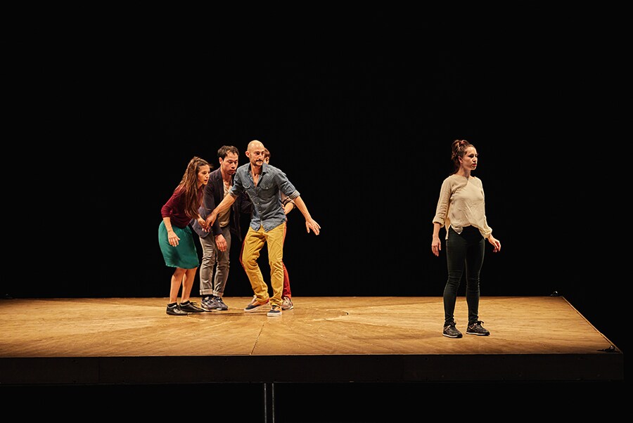 Ein Foto einer Frau, die am Rand einer Fläche steht, und vier weiteren Personen, die von der anderen Seite der Fläche zu ihr hinübersehen.