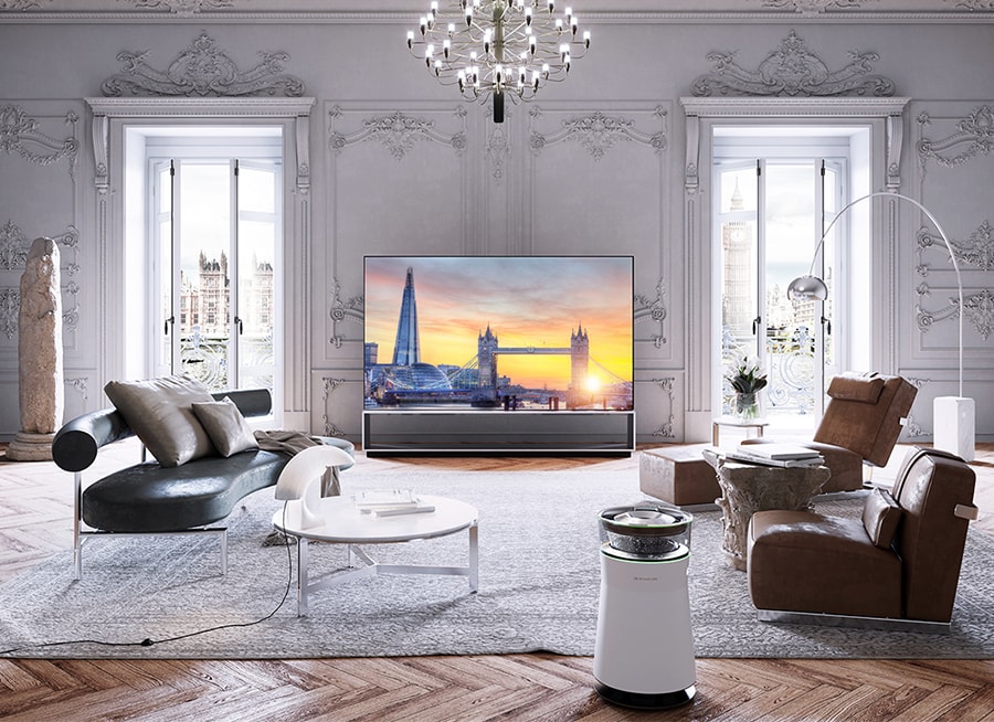 Ein OLED 8K-Fernseher von LG SIGNATURE wurde in einem Raum mit viktorianischen Gesimsen und Parkettböden sowie Einrichtungsgegenständen von Flexform aufgestellt.