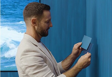 Darren Palmer steht vor der blauen Wand und hält und schaut in die kleine blaue Farbpalette