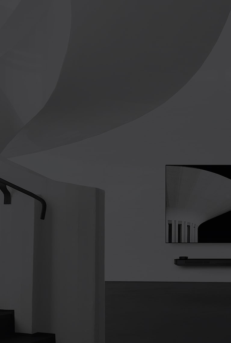 Ein Schwarz-Weiß-Bild von dem lg signature OLED TV, das links der Wand hängt und links davon befindet sich eine Wendeltreppe
