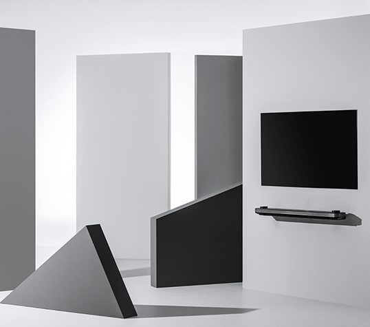 Der LG SIGNATURE OLED TV W ist an einer Wand angebracht, umgeben von geometrischen Figuren.