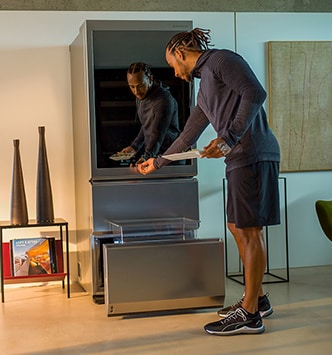 Lewis Hamilton gibt etwas auf dem Glas-Touchdisplay des LG SIGNATURE Weinkühlschranks ein.