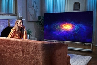 Olivia Palermo entspannt vor ihrem LG SIGNATURE OLED 8K-Fernseher auf ihrer Couch.