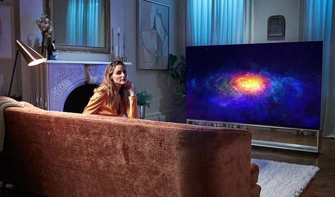 Olivia Palermo entspannt vor ihrem LG SIGNATURE OLED 8K-Fernseher auf ihrer Couch.