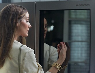 Olivia Palermo klopft zweimal sanft an die Instaview-Glasscheibe des LG SIGNATURE Kühlschranks.