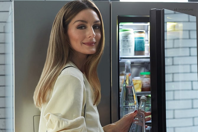 Olivia Palermo öffnet die Instaview-Glasscheibe des LG SIGNATURE Kühlschranks und gewährt einen Blick auf ihre Lieblingssnacks.