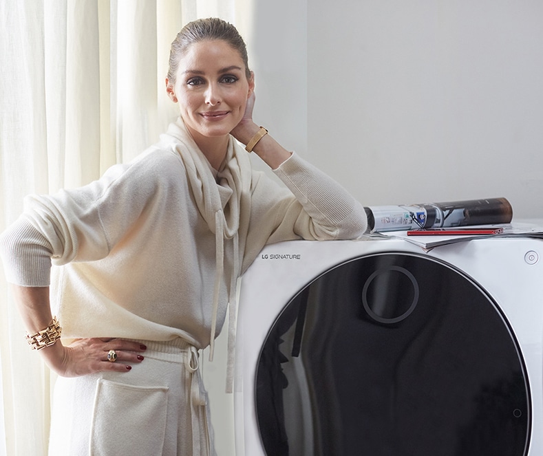 Olivia Palermo stützt ihre Arme auf die LG SIGNATURE Waschmaschine.