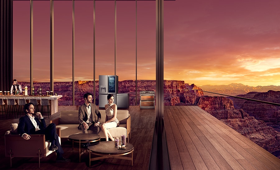 Eine kleine Gruppe von Menschen sieht sich bei Sonnenuntergang die Canyons aus einem Outdoor-Essbereich an, in dem ein Kühlschrank, ein Backofen und eine Geschirrspülmaschine von LG SIGNATURE stehen.