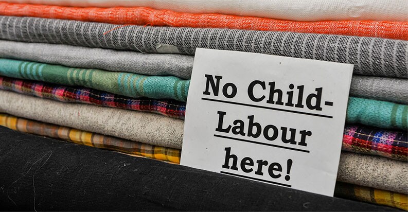 Billede af 'Ingen børnearbejde hende!' tegn foran tekstiler