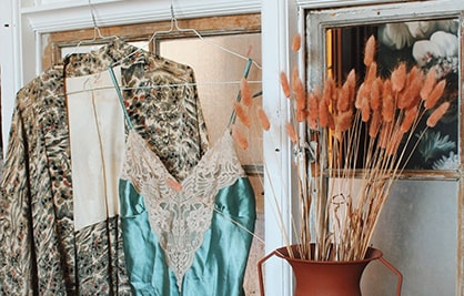 Et miniaturebillede af to hængende vintage tøj og en vase med baggrunden af vinduet.
