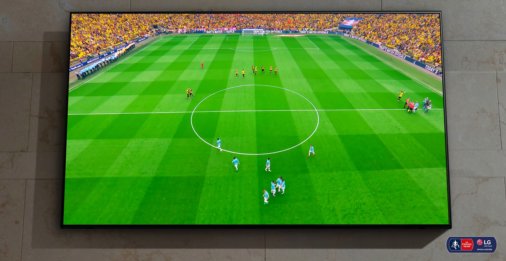 Der er et vægmonteret NanoCell-TV. En fodboldkamp skal til at starte på skærmen.