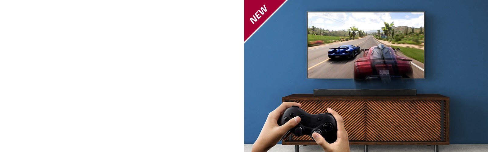 Un téléviseur LG est installé au mur, montrant un jeu de course. La barre de son LG est installée sur l’étagère marron, juste en dessous du téléviseur LG. Un homme tient un joystick. La marque NEW est affichée dans le coin supérieur gauche.