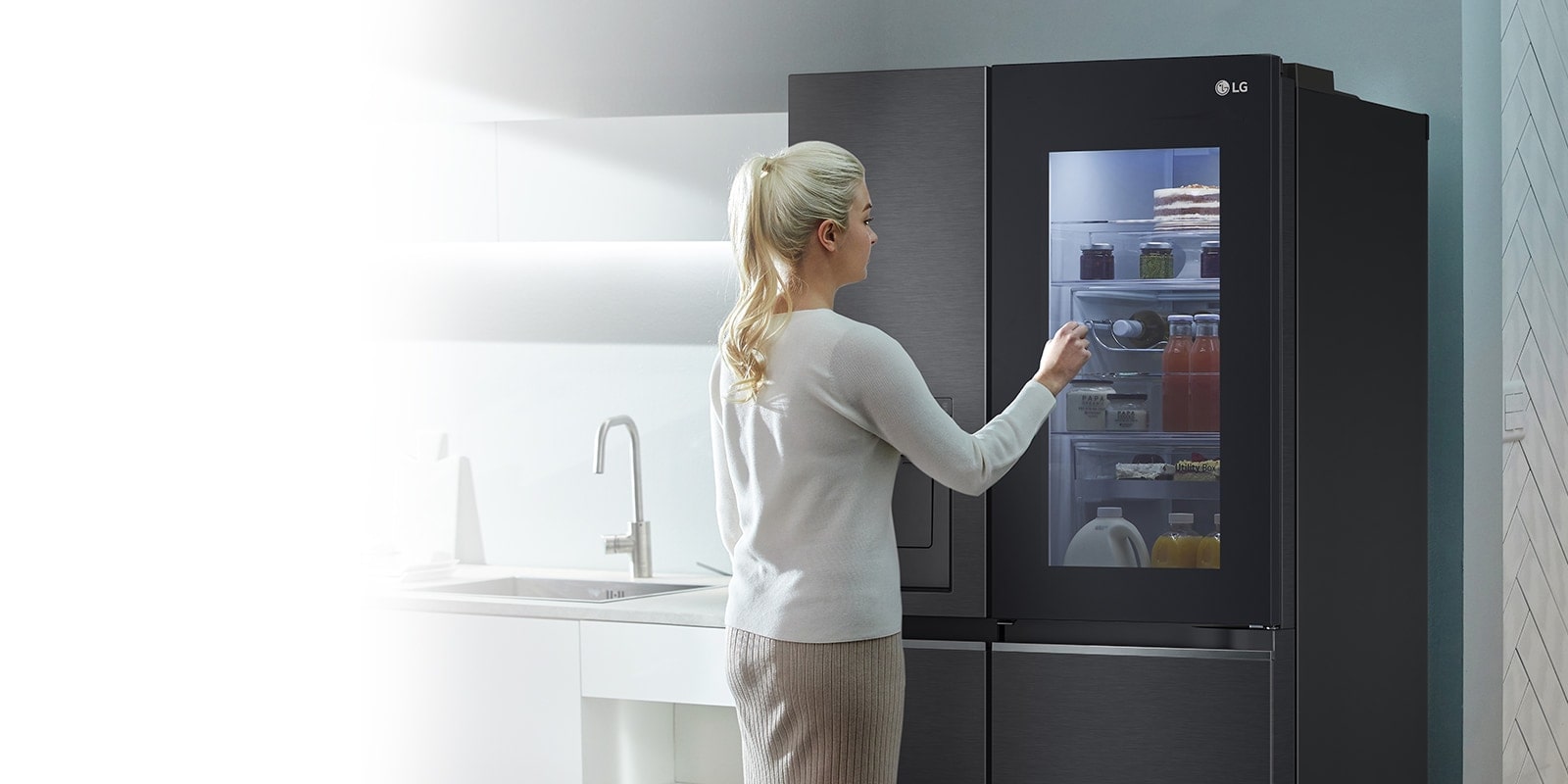 Une image montre une femme devant son réfrigérateur InstaView en train de toquer. L’intérieur du réfrigérateur s’allume et elle peut voir son contenu sans ouvrir la porte.